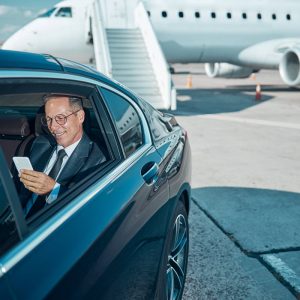 cheerful-businessman-with-smartphone-in-car-at-air-2022-02-04-01-15-11-utc